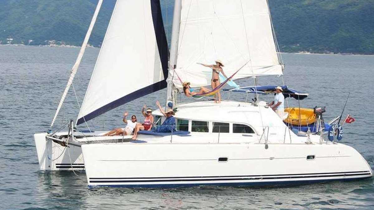 Friends relaxing on the trampoline of a Lagoon 38 catamaran under sail, an affordable group yacht charter in Puerto Vallarta