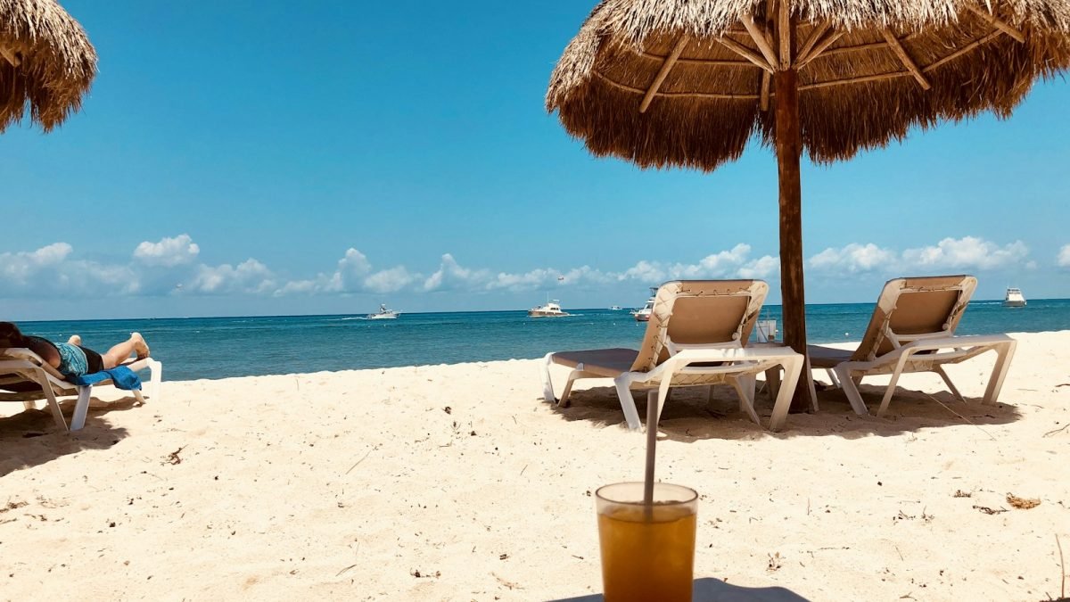 brown parasol and two beach chairs on beach sand